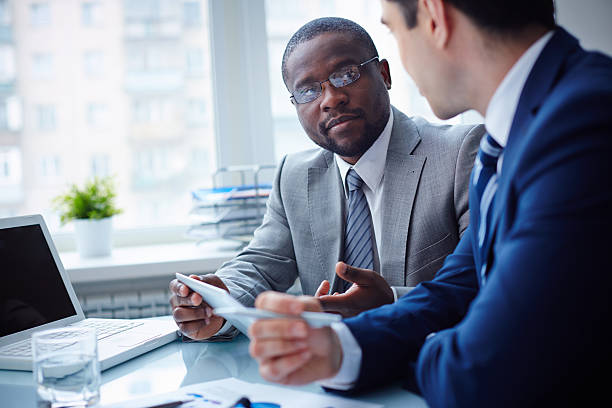 Image of two young businessmen interacting at meeting in office